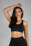 Woman wearing a black sports bra with 'Ultra' branding on a gray background